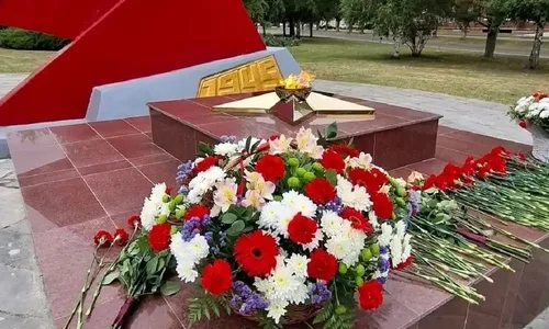 Группа людей у монумента с огнем, символизирующим память о героях войны, в Курчатове.