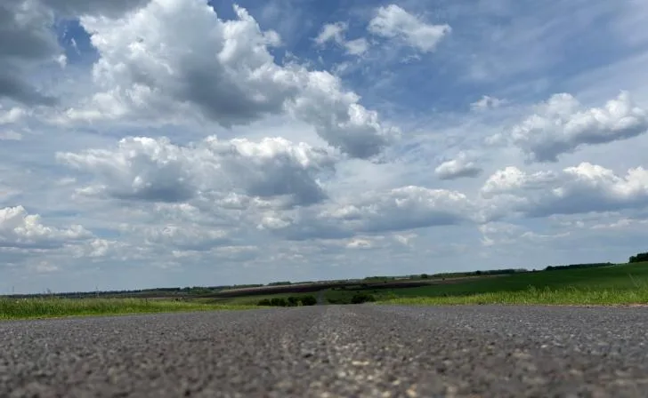 Дорога рядом с областной больницей в Курске, требующая ремонта, с ямами и дефектами.